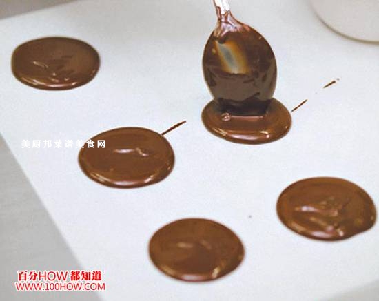 意式脆口坚果片的制作方法2,将融化的巧克力用汤匙舀在烤盘纸上,并抹开成薄圆形。